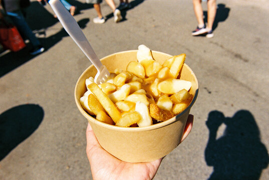 POV of person holding to-go container of poutine on the street