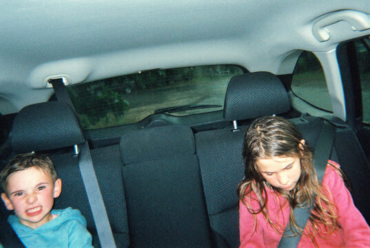 Candid film photo of two kids in the back of a car