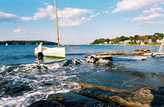 Man getting sailboat onto trailer