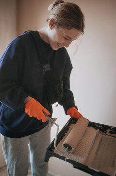 Young woman painting a room with a roller