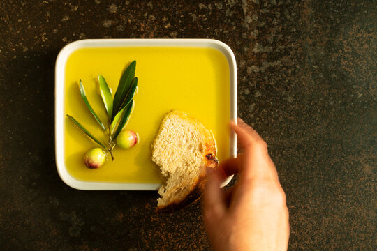 Hand reaching for bread in a plate with olive oil