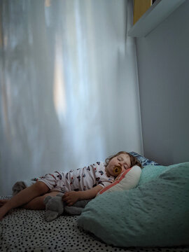 A toddler having a nap while light from outside makes patterns
