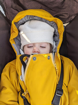 Baby with a pacifier asleep in her stroller wearing a winter coat