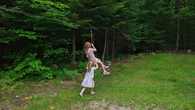 Two girls play on a zipline