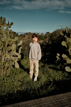 Young boy standing outdoors among green prickly pear cactus
