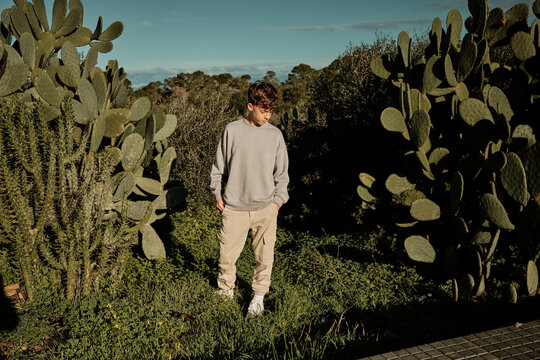 Young boy contemplating in a green cactus garden