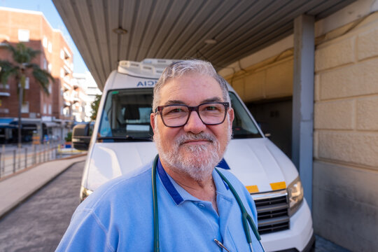 Senior paramedic wearing uniform standing in front of ambulance