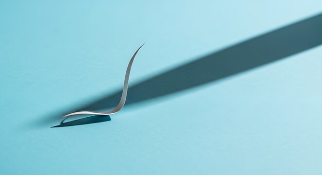 A single false eyelash being applied with a tweezer on a light blue background