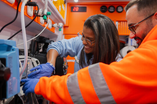 Paramedics training on medical equipment in ambulance