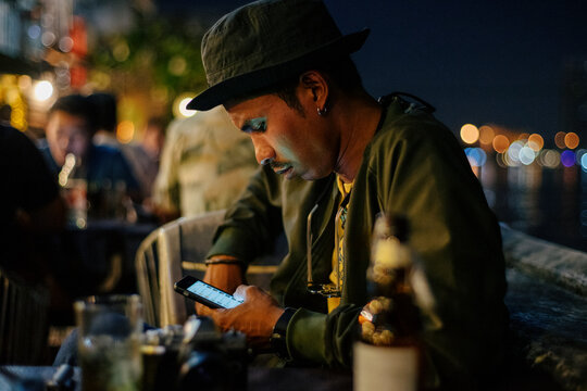 Portrait of a young man checking his smartphone in the pub at night