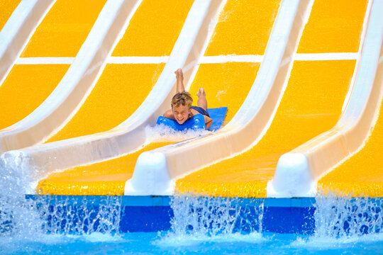 Boy having fun sliding down water park slide