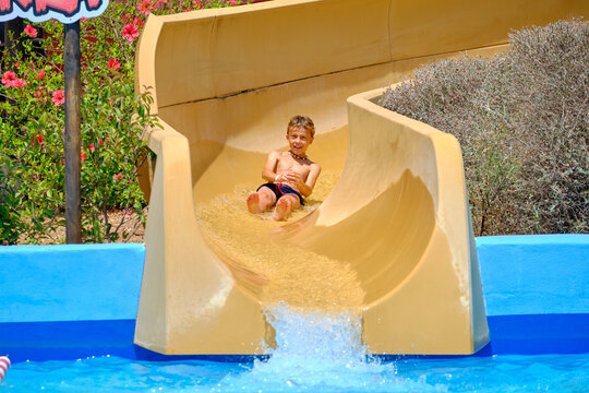 Boy sliding down water slide having summer fun
