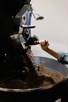 Partial view of female worker controlling process of coffee roasting