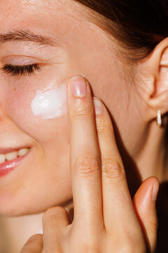 Close-up of woman applying cream on cheek skincare 