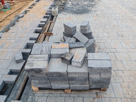 Interlocking pavers, small brick-like tiles, for pavement areas, walkways, pedestrian crossings and paved pathways Interlock pallets on construction site, ready for installation on landscaping paving.