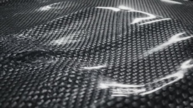 Close-up view of a carbon fiber surface with a textured pattern and white streaks