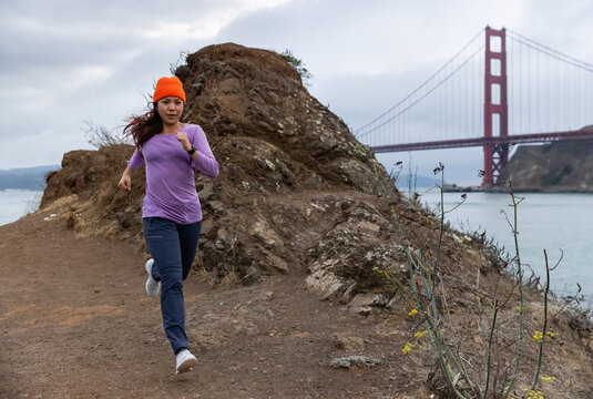 Asian girl athlete athlete trail run  Golden Gate Bridge 