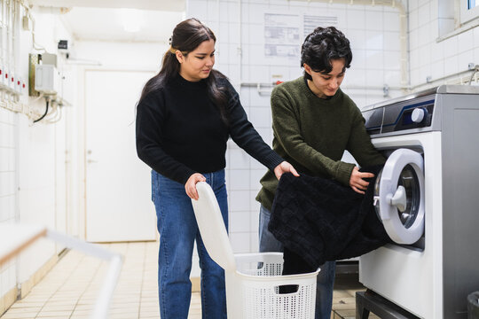 Lesbian Couple Collaborating on Laundry Chores in Washroom