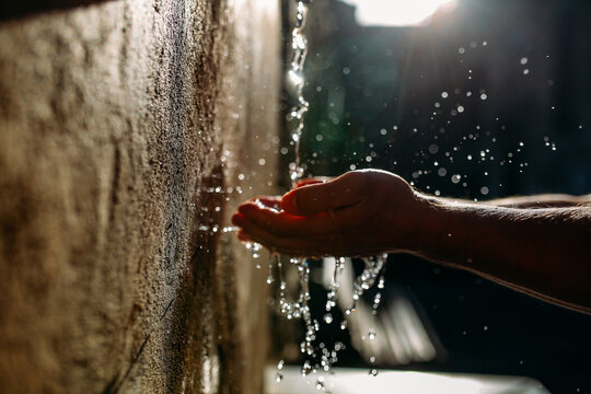 Water falling from wall into a person&rsquo;s hand
