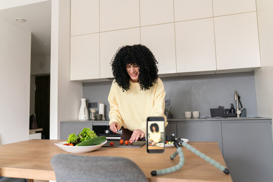 Woman filming cooking tutorial in modern kitchen
