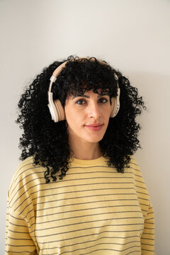 Woman with curly hair listening to music on headphones