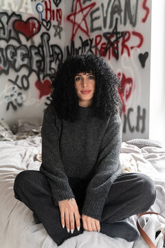 Woman sitting on bed with graffiti wall background