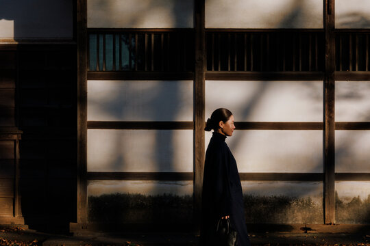 Elegant Woman Strolling in an Old Alley Amidst Light and Shadow.