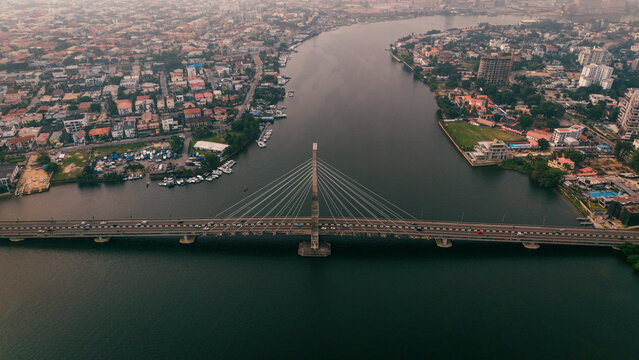 Aerial view of Lekki-Ikoyi Link Bridge over the still, dark water, connecting vibrant urban landscapes under a hazy sky, Lagos, Lagos, Nigeria.