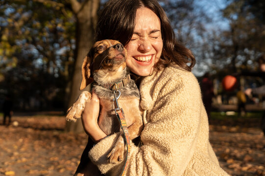 Woman Happily Embraces Her Dog in a Sunny Park During Autumn