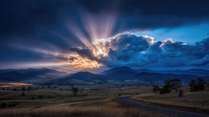 Dramatic Sunset Over Rolling Hills and Mountains with Cloudy Sky and Rays of Light Shining Through the Landscape During the Evening Twilight