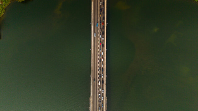 Aerial view of Lekki-Ikoyi Link Bridge cutting through the dark waters with a string of colourful cars, Lagos, Nigeria.