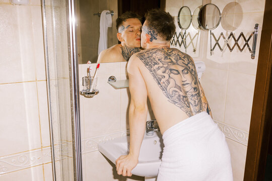 Person With Tattoos Admiring Reflection in Bathroom Mirror