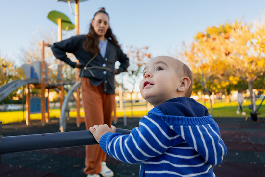 Baby boy playing park with mother observing