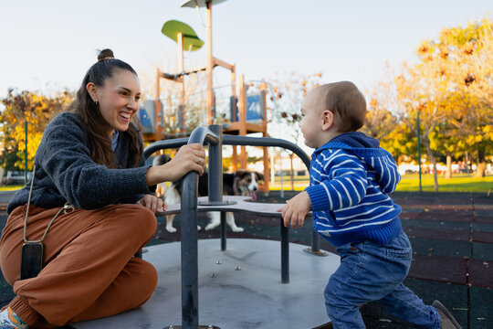 Mother and son playing on a carousel in park