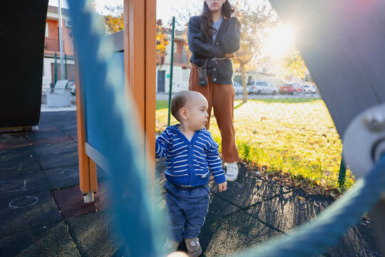 Toddler playing at playground while mother observing