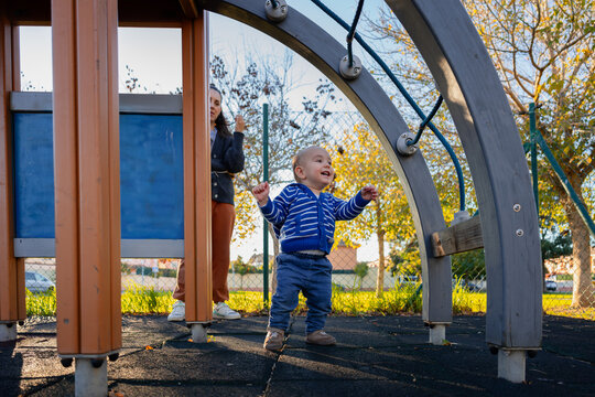 Toddler playing in outdoor playground with mother