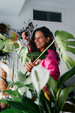Woman misting the leaves of her houseplants
