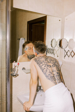 Man With Tattoo in Bathroom Mirror Reflecting Intimate Moment