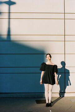 Woman standing against modern wall at sunset