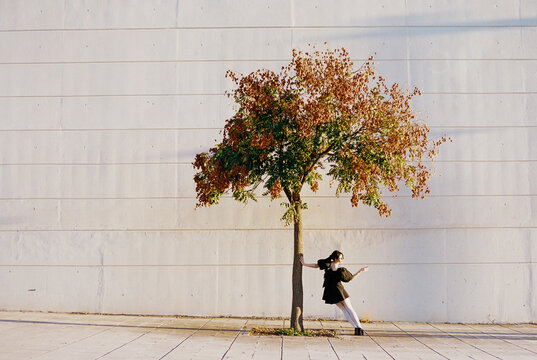 Dancer leaning from tree in afternoon light