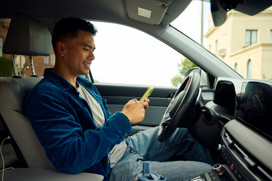 Good-looking man is on his phone in a car.