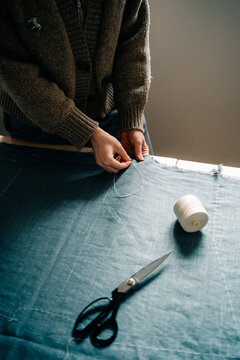 Sewing a Blue Fabric With Thread and Scissors in a Cozy Workspace