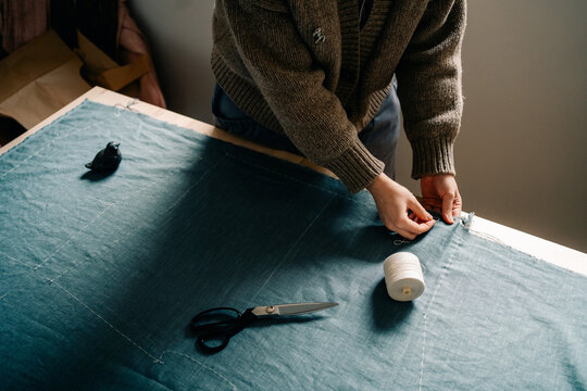 Sewing Fabric With Scissors and Thread at a Cozy Workspace
