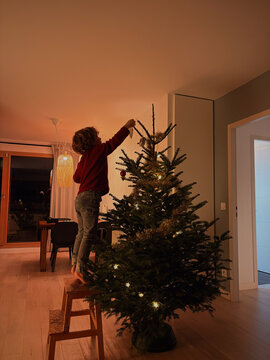 child decorating Christmas tree at home