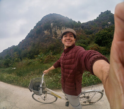 Traveler taking selfie while riding bicycle near limestone hills