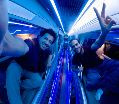 Two men posing for selfie inside illuminated sleeper bus