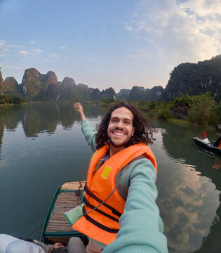 Traveler posing on boat while pointing toward limestone cliffs