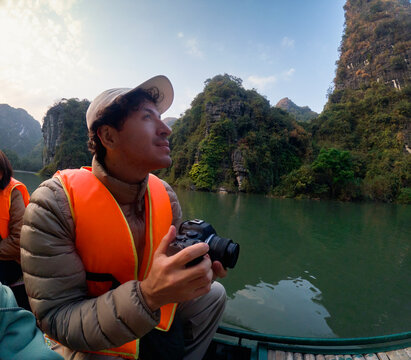 Traveler holding camera while sightseeing on river boat