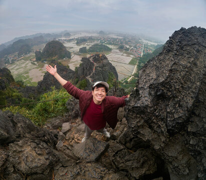 Traveler climbing rocks at panoramic mountain viewpoint