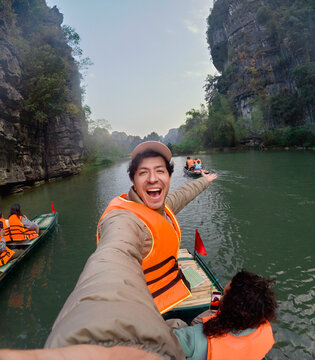 Traveler taking selfie during boat ride through river canyon